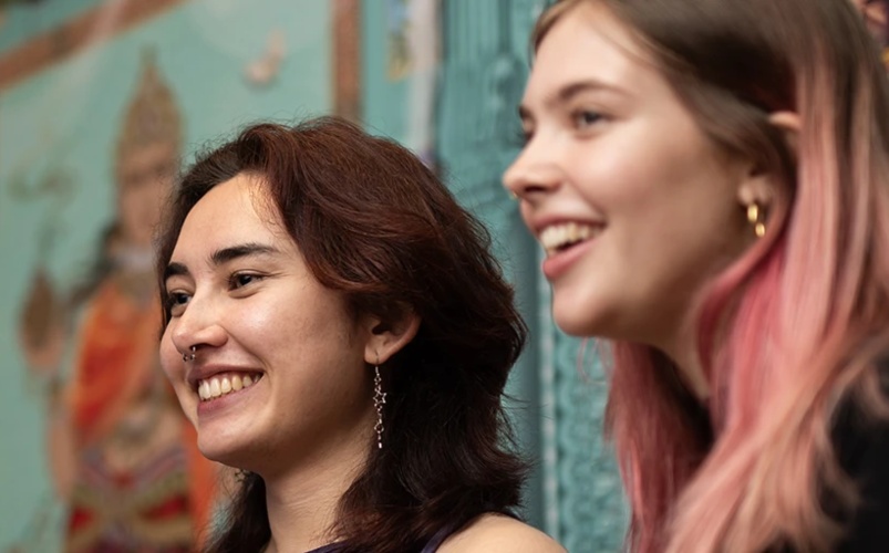 Students smiling next to artwork in a museum