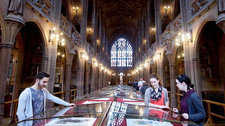 Students looking at books in glass casing in John Rylands Library
