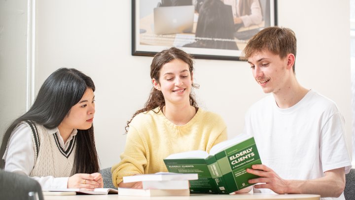 Group of students looking at a textbook