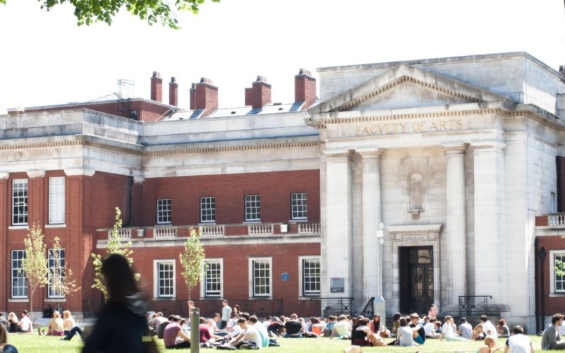 University of Manchester campus and buildings, with groups of students siting on the grass