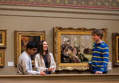 Group of students laughing whilst standing in an art gallery