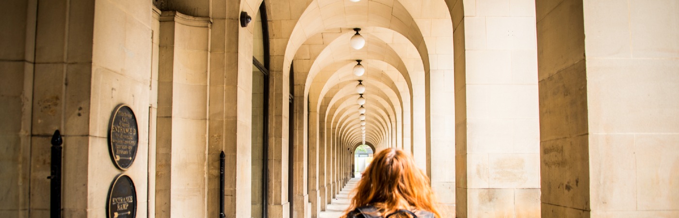 Female student walking through the arches at Manchester City Library.