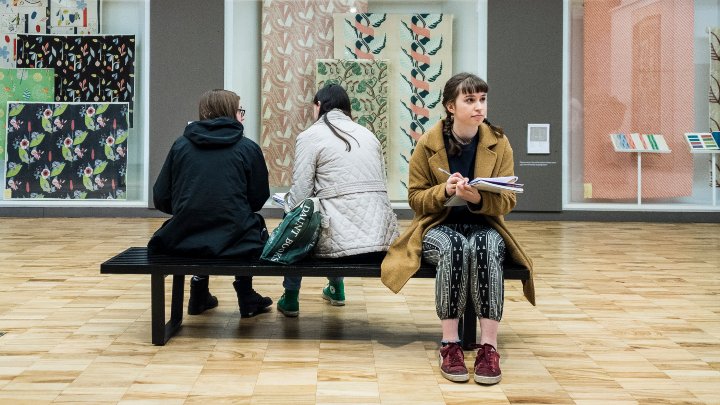 Students sat on a bench in an art gallery