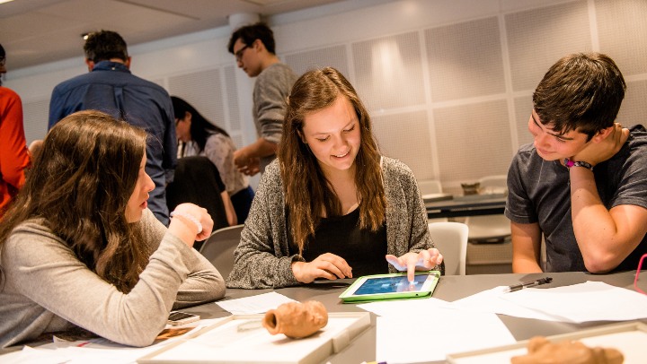 Group of students sat looking at an iPad