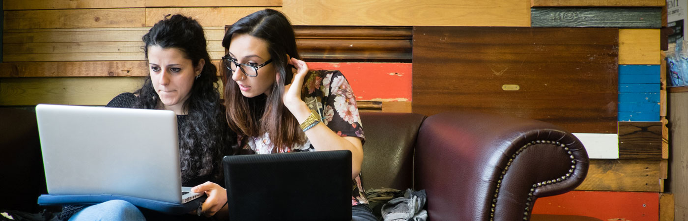 Two students working on laptops together