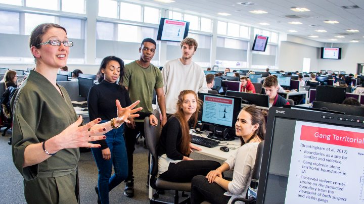 Academic speaking to students gathered around a computer screen