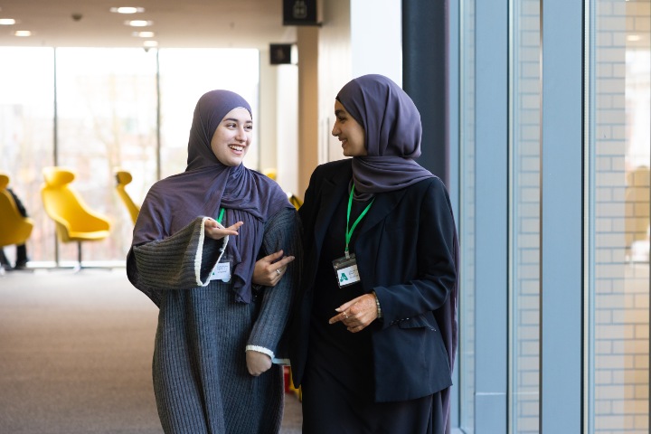 Students wearing head coverings walking down a coridoor 