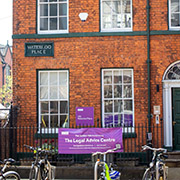 Legal Advice Centre on Waterloo Place in a red brick building with purple sign and parked bicycles.
