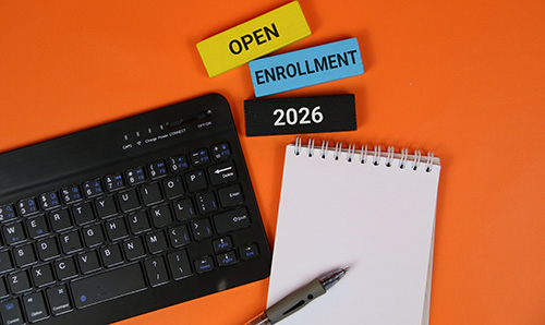 Open Enrolment 2026 blocks with keyboard, notepad and pen on bright orange background for admissions.
