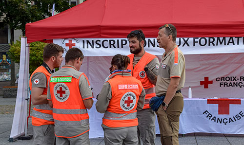 French Red Cross volunteers speaking at an event registration tent.