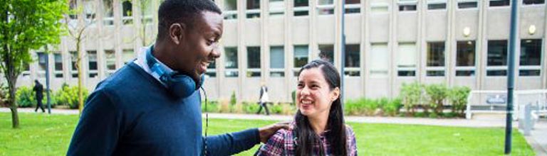 Two PhD students walking past the Arthur Lewis building