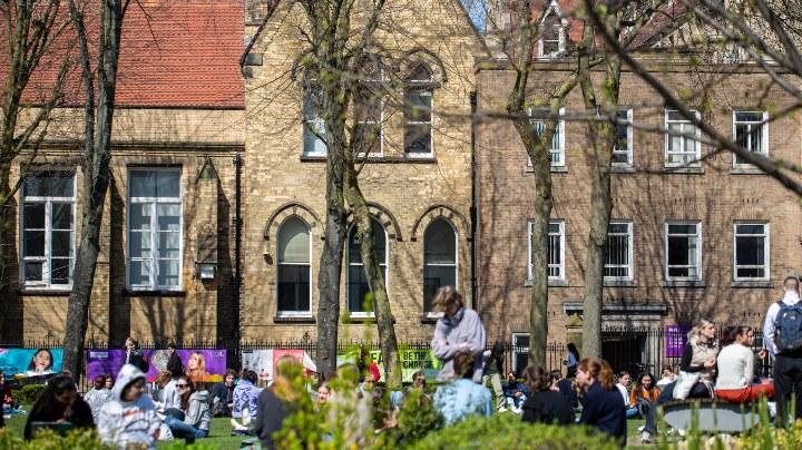 Students sat on the grass outside a university building 