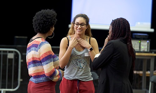 Three female students in front of a screen