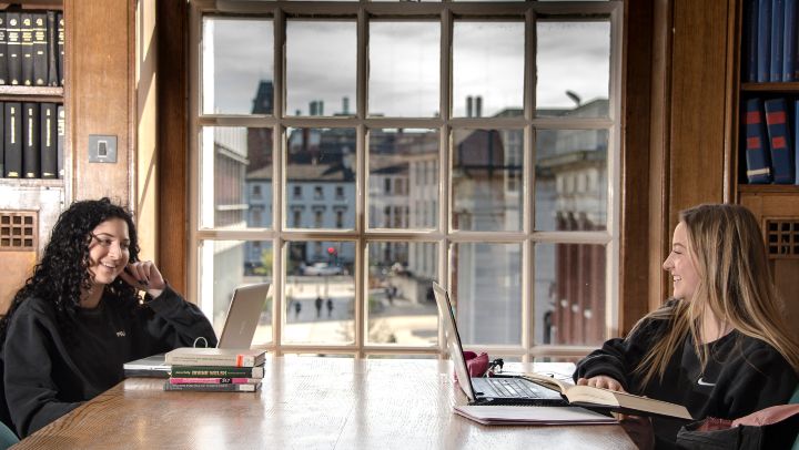 Students sat at a table with their laptops and books