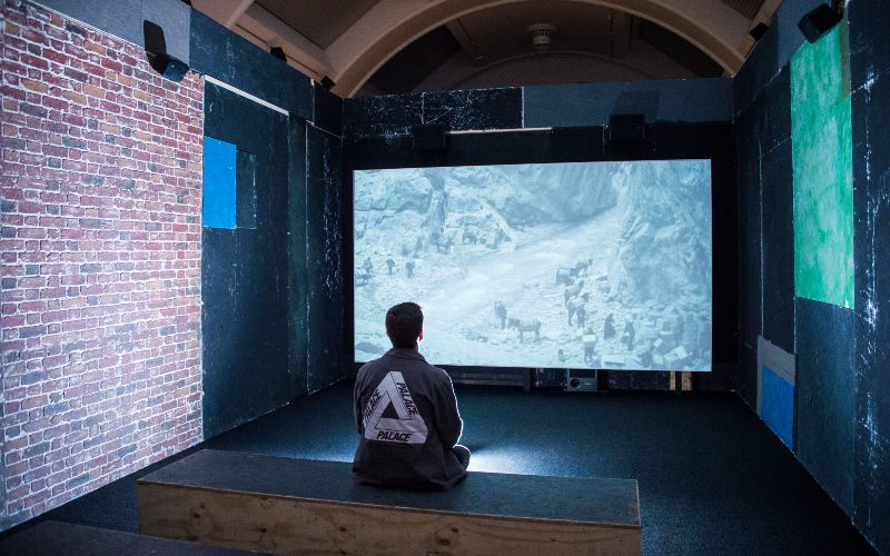 Student sat in a room watching a film projection