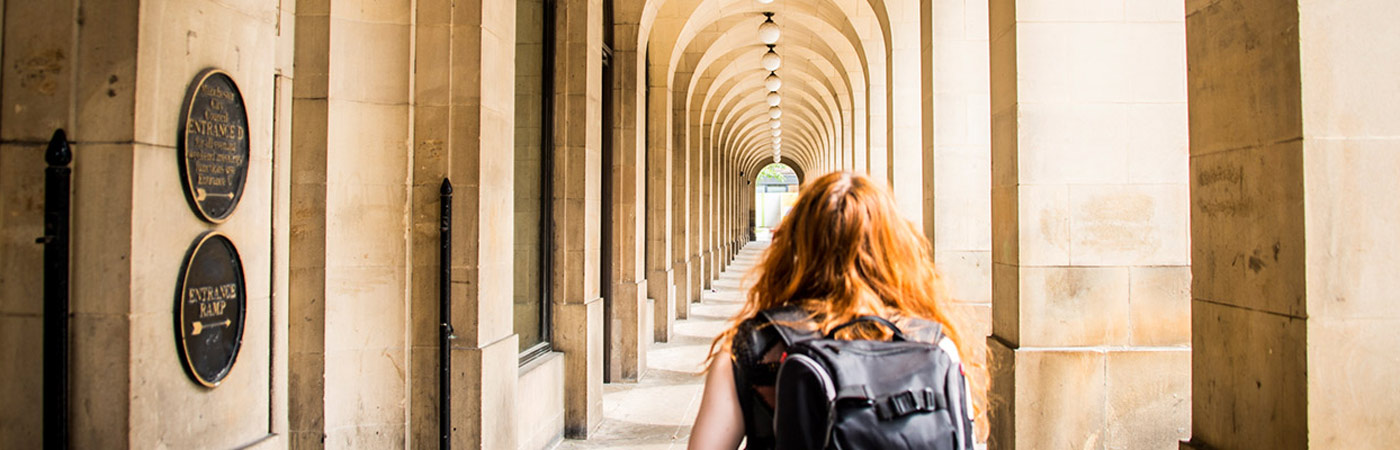 Female student walking through outside corridor