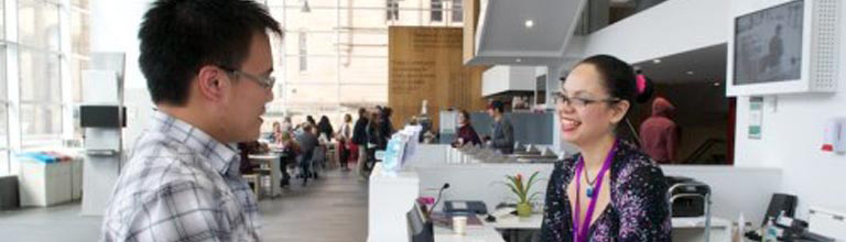 A male student talking to a female staff member in the Library