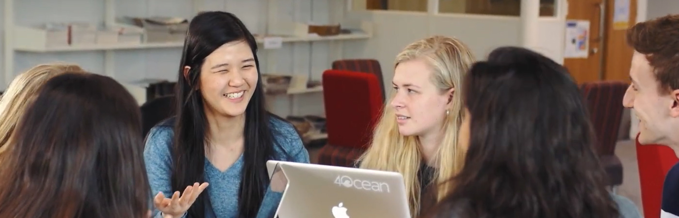 International undergraduate students chatting around a laptop
