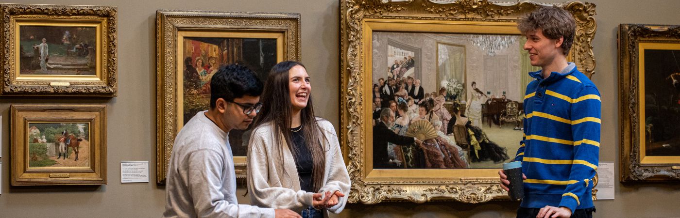 Students laughing in an Art Gallery surrounded by old paintings 