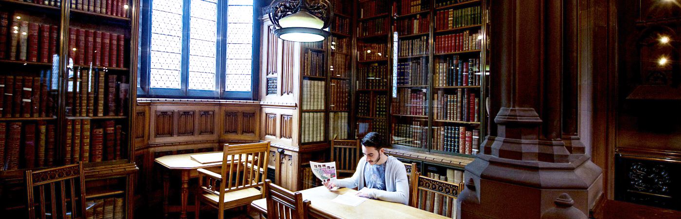 Student sat reading at a table in an old gothic library