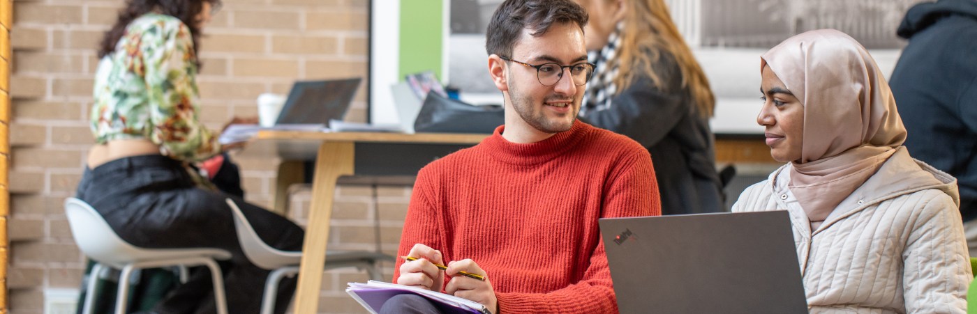 Students sat talking to each other with a laptop