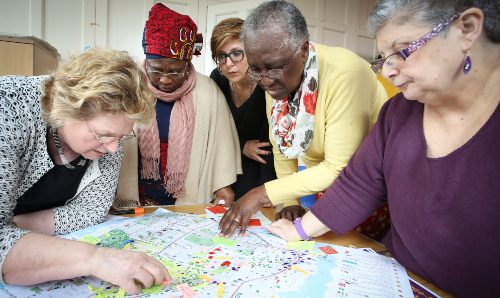 A group of people surrounding a table, looking at a map.
