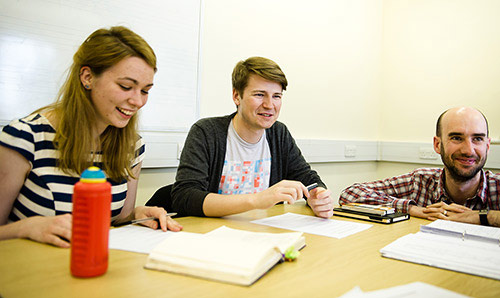Three students sat at table smiling