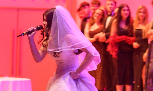 Female student dressed as a bride performing on stage.