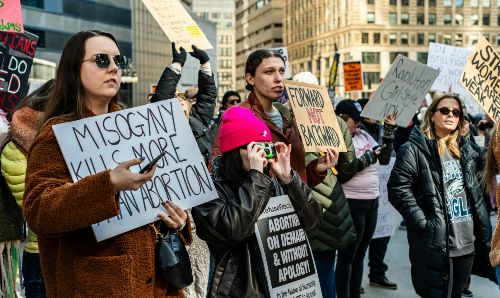 Women protesting and holding signs against misogyny.