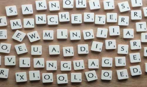Many blocks with different letters written on them, scattered on a table.