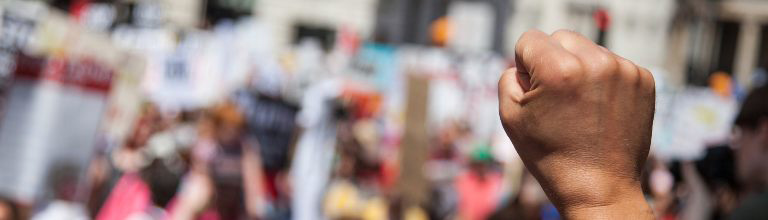 Close up of a single fist in the air at a protest.