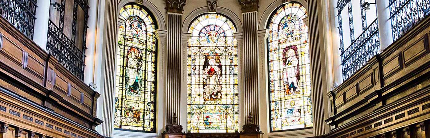Three large stained glass windows in a church interior