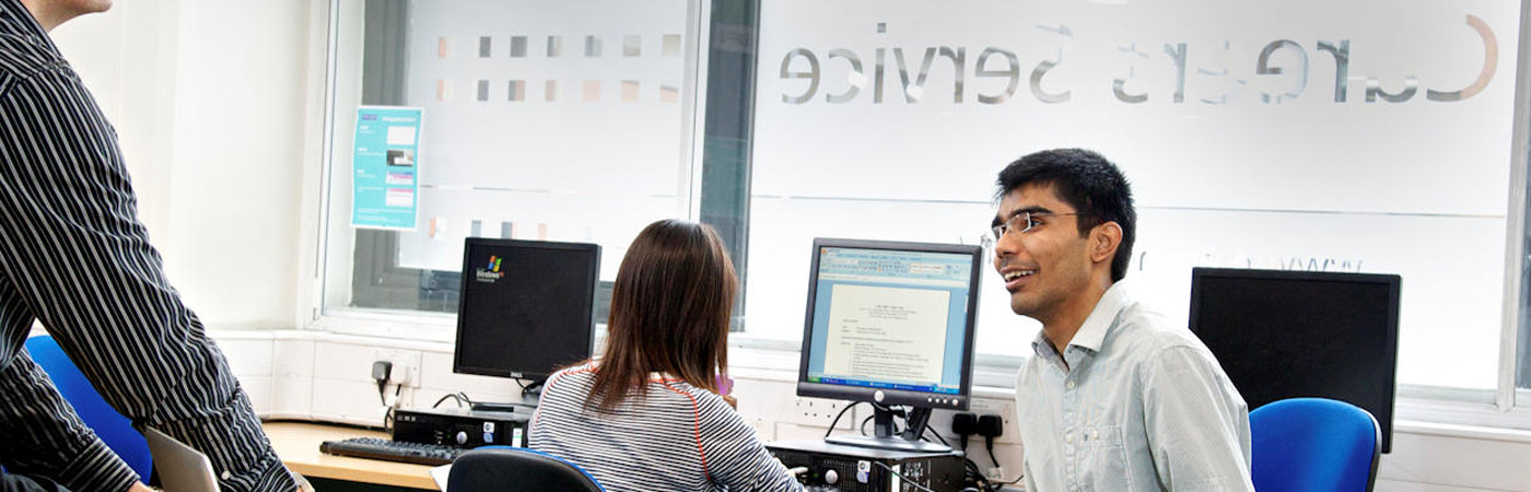 Students chatting and smiling in a computer cluster at the University's Career Service