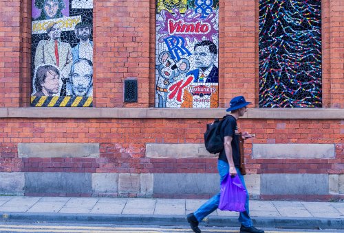 Person walking past a wall of graffiti in the street 