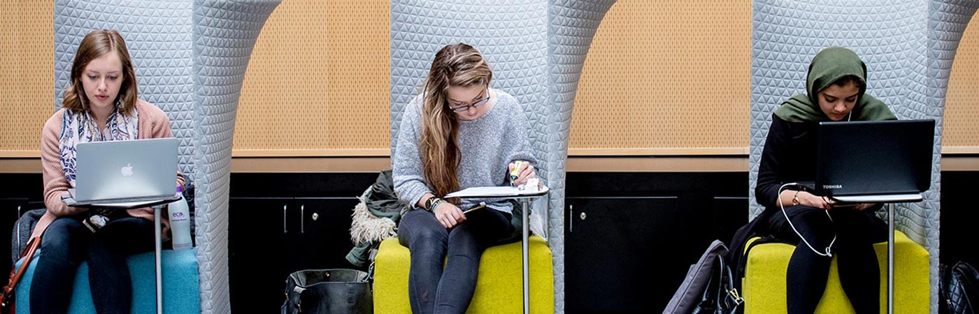 Three people sat on chairs in a study area working on laptops