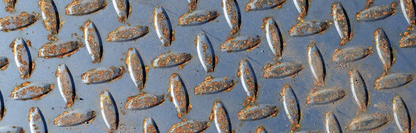 Close up photograph of textured metal flooring, slightly rusting.