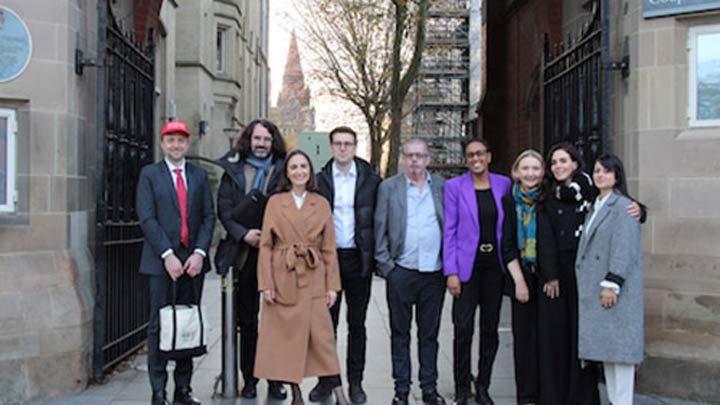 A group of Manchester International Law Centre staff standing together under a stone archway
