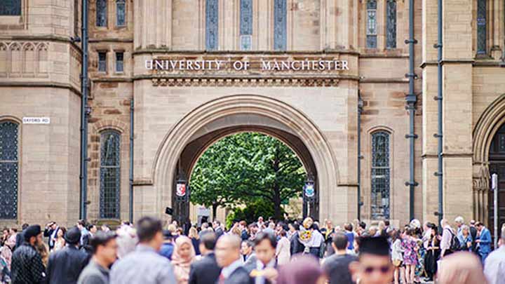 A crowd gathers at the University of Manchester's archway on Oxford Road.