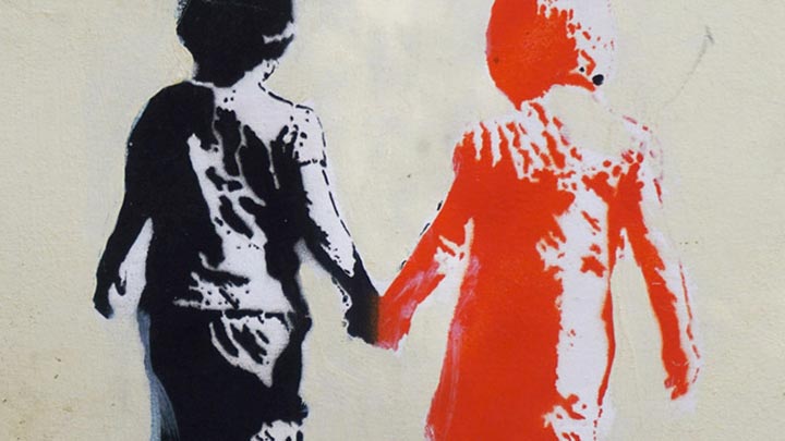 Grafitti stencil on a wall of two children holding hands