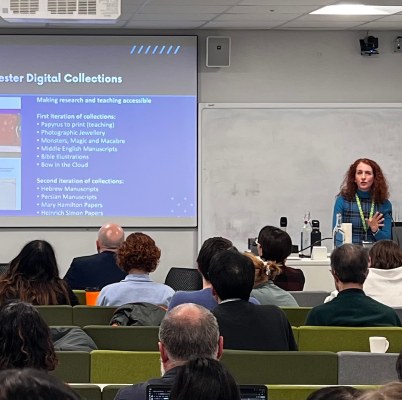 Academic speaking to a room of people sat looking at a digital screen 