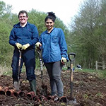 Two people in a filed with spades and pots