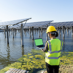 Person with hard hat on at the side of water.