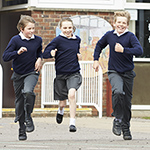 Group Of Elementary School Pupils Running In Playground