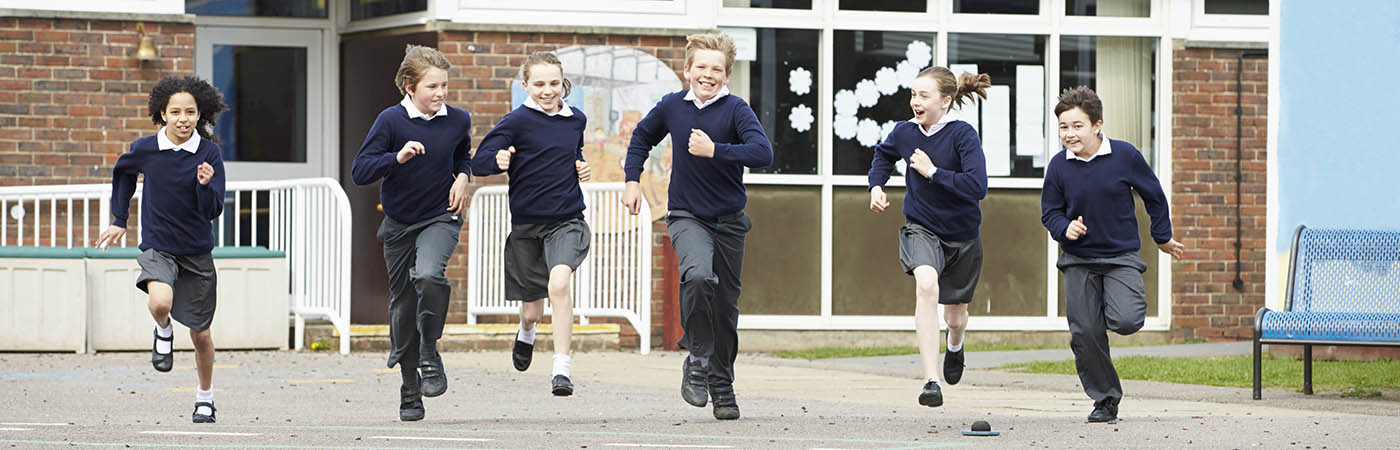 Group Of Elementary School Pupils Running In Playground
