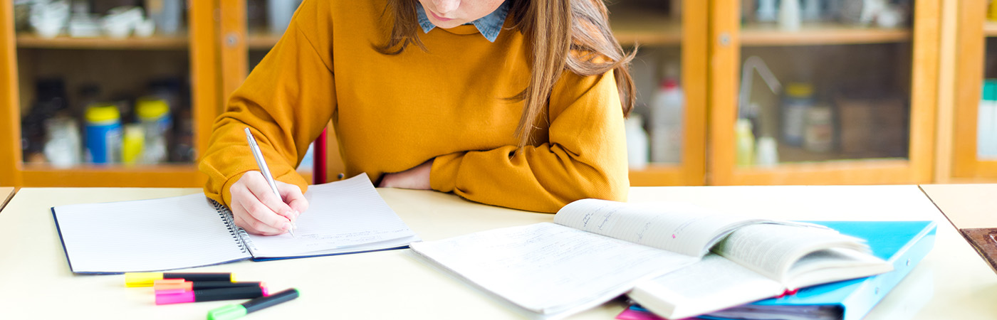 Student sat at a desk, writing in a notebook