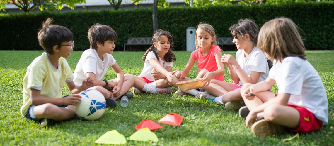 An image of children seated in a green space.