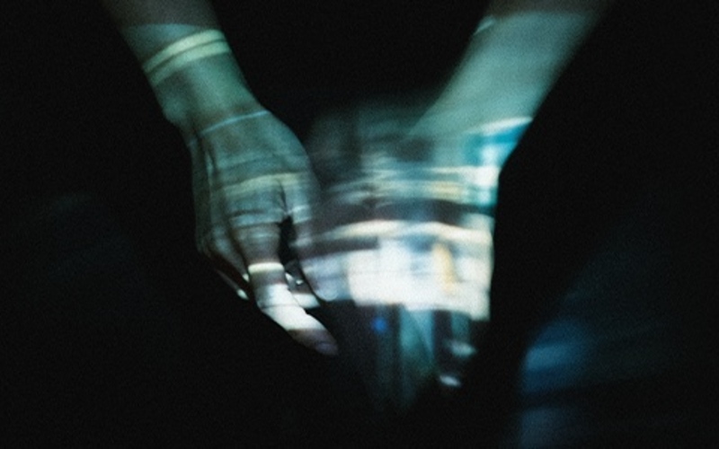 Blurred white hands on a black background. Image credit to Sian Fan.