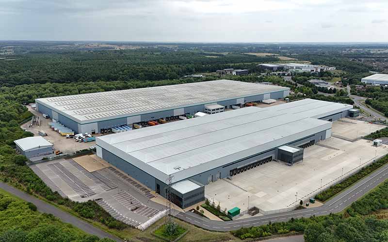 Aerial view of a large distribution warehouse with loading bays and surrounding woodland.