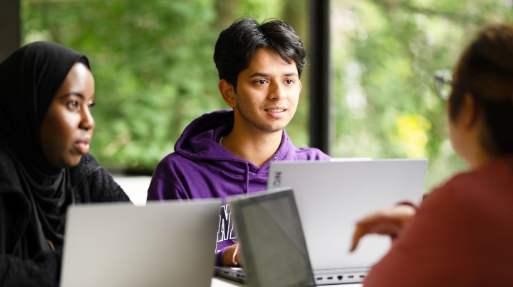 Students chatting at a table with their laptops 
