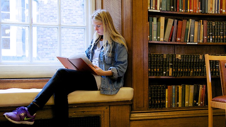 Student reading a book by the window